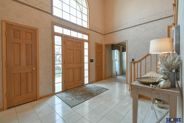 entrance foyer featuring stairway, a towering ceiling, and light tile patterned flooring