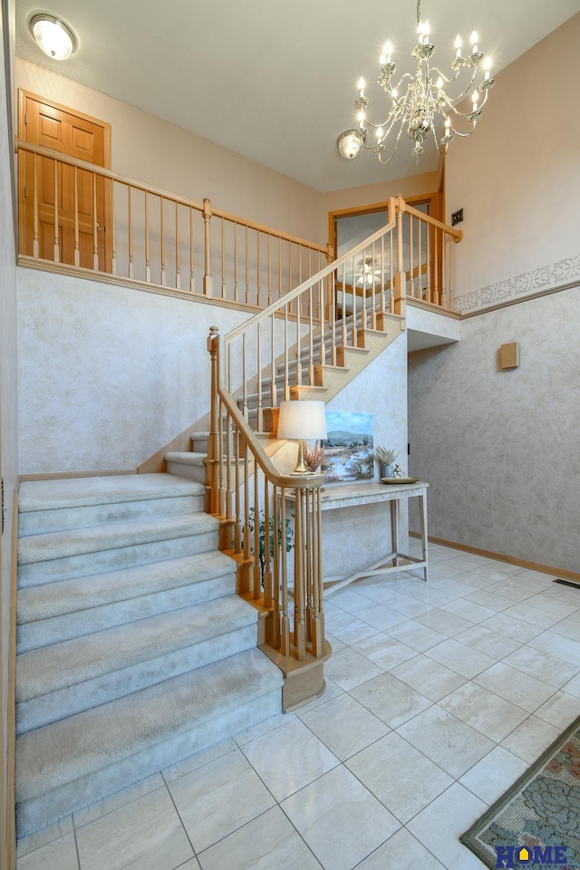 staircase with tile patterned floors, baseboards, and a towering ceiling