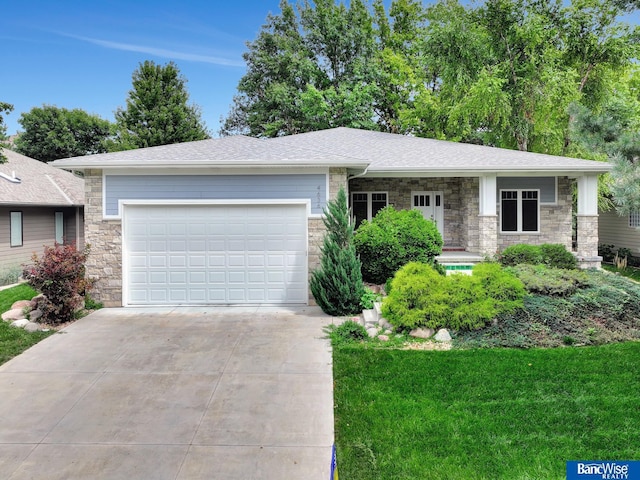 view of front of house featuring a shingled roof, concrete driveway, an attached garage, a front yard, and stone siding