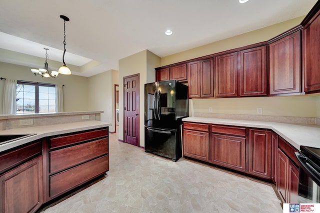 kitchen featuring decorative light fixtures, light countertops, freestanding refrigerator, and an inviting chandelier