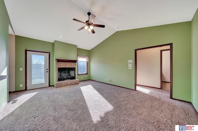 unfurnished living room featuring a ceiling fan, baseboards, carpet floors, vaulted ceiling, and a tiled fireplace