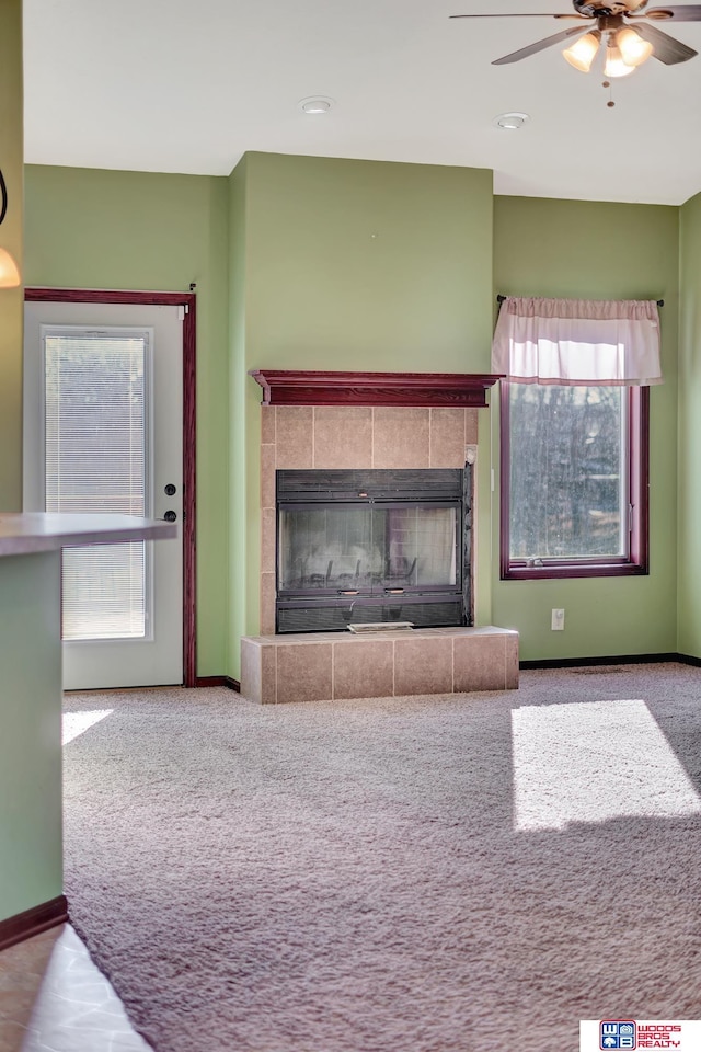 unfurnished living room featuring baseboards, carpet, ceiling fan, and a fireplace