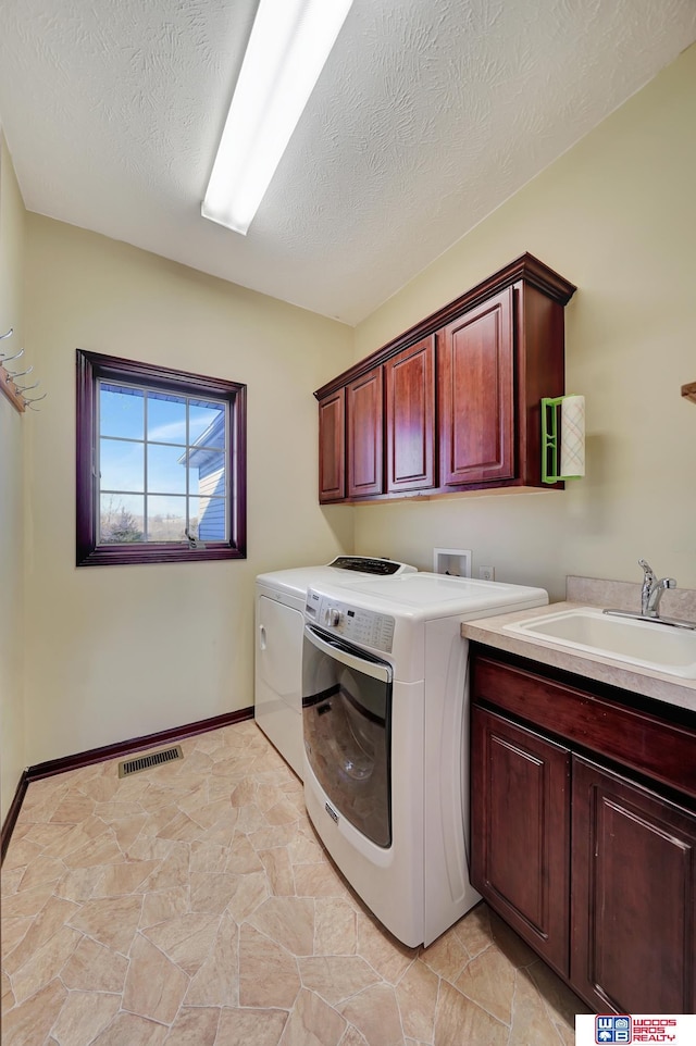 laundry area with visible vents, a sink, washer and dryer, a textured ceiling, and cabinet space