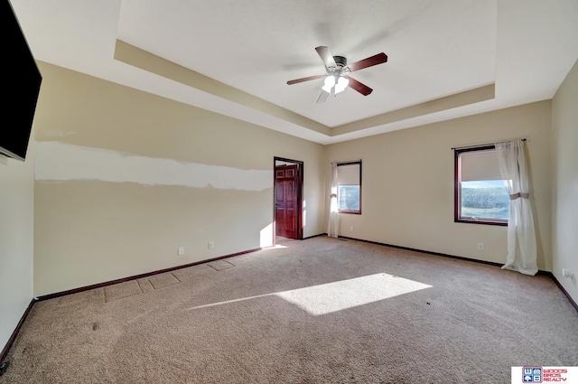 unfurnished room with baseboards, a raised ceiling, ceiling fan, and carpet flooring