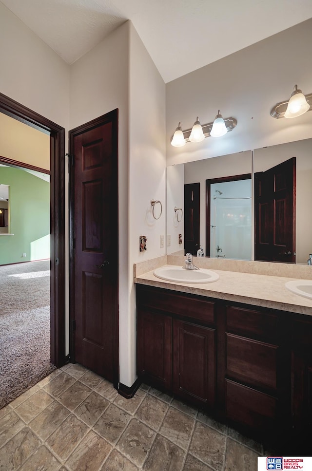 full bath with double vanity, stone finish flooring, and a sink