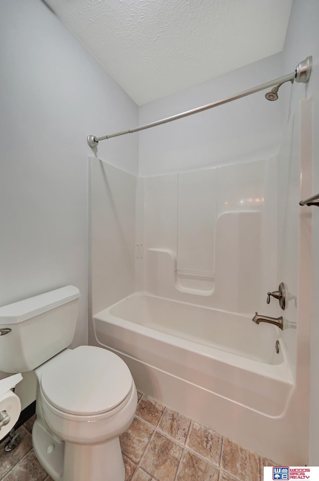 bathroom featuring a textured ceiling, toilet, and bathing tub / shower combination