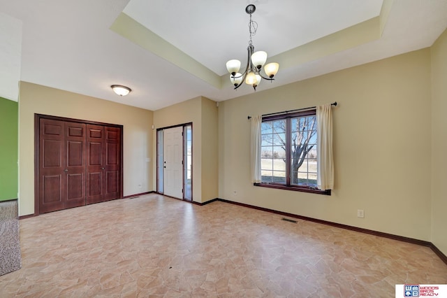 foyer entrance with visible vents, an inviting chandelier, baseboards, and a tray ceiling