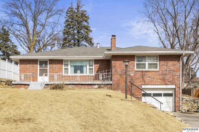 view of front of property with a front yard, brick siding, a chimney, and an attached garage