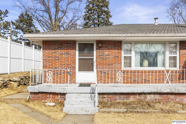 entrance to property featuring brick siding and fence