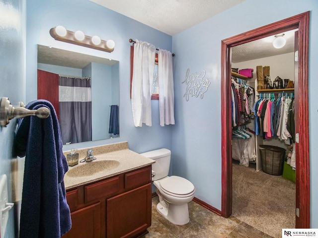 full bathroom featuring a walk in closet, a textured ceiling, curtained shower, vanity, and toilet