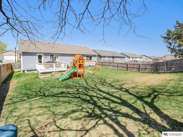 view of yard featuring a playground, a wooden deck, and a fenced backyard