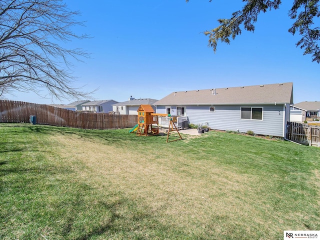 back of property featuring a playground, a lawn, and a fenced backyard