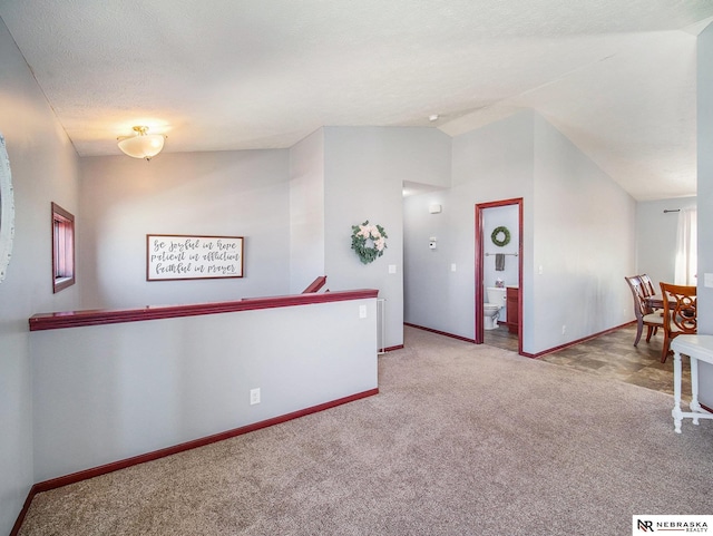 interior space with baseboards, carpet, and vaulted ceiling