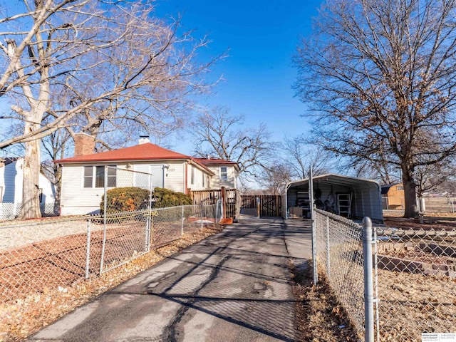 view of front facade with a carport, driveway, fence, and a chimney