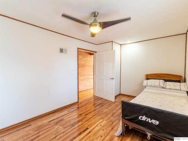 bedroom featuring ornamental molding, light wood-type flooring, visible vents, and baseboards