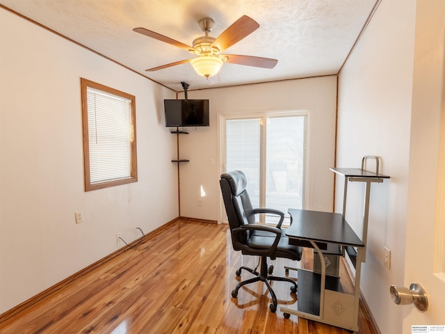 office featuring a textured ceiling, light wood-type flooring, and a ceiling fan