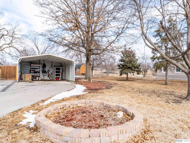 view of yard with fence, concrete driveway, and a detached carport