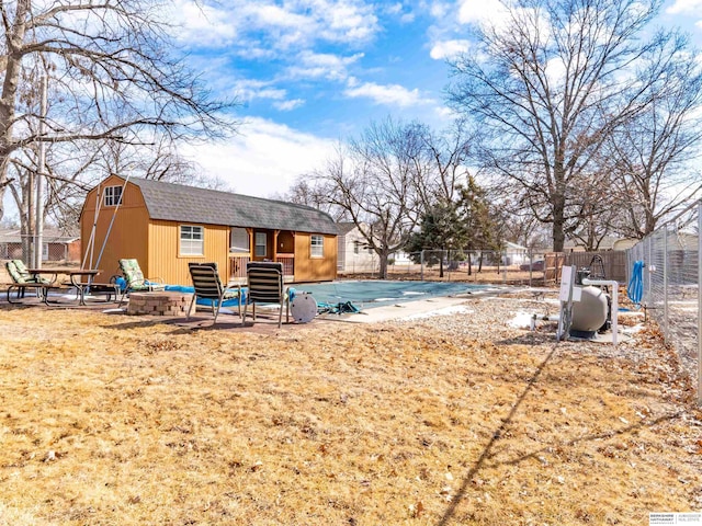 rear view of house with a patio, a shingled roof, an outdoor fire pit, fence, and an outdoor structure