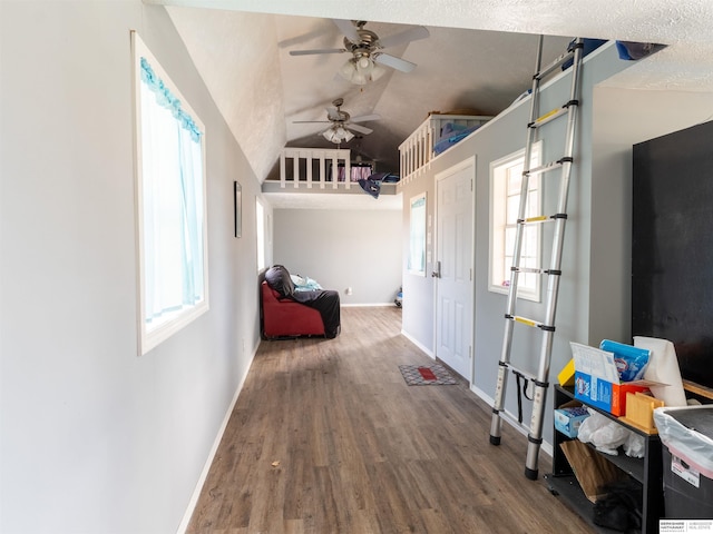 corridor featuring lofted ceiling, a textured ceiling, baseboards, and wood finished floors