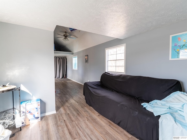 living room with lofted ceiling, ceiling fan, a textured ceiling, wood finished floors, and baseboards