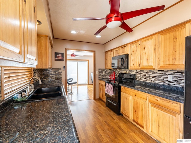 kitchen featuring a sink, a ceiling fan, black appliances, light wood finished floors, and tasteful backsplash