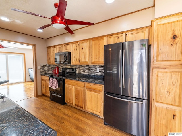 kitchen featuring a ceiling fan, backsplash, dark stone counters, black appliances, and light wood finished floors