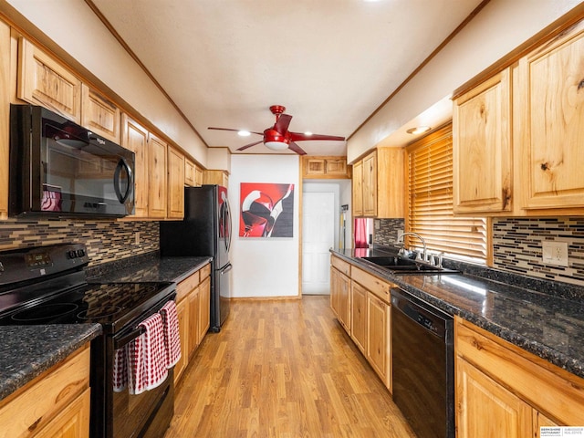 kitchen with dark stone counters, a ceiling fan, light wood-type flooring, black appliances, and a sink