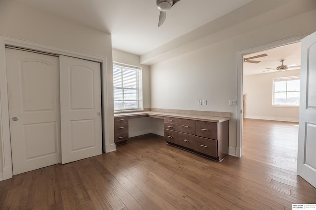 unfurnished bedroom with a closet, baseboards, wood finished floors, and built in study area