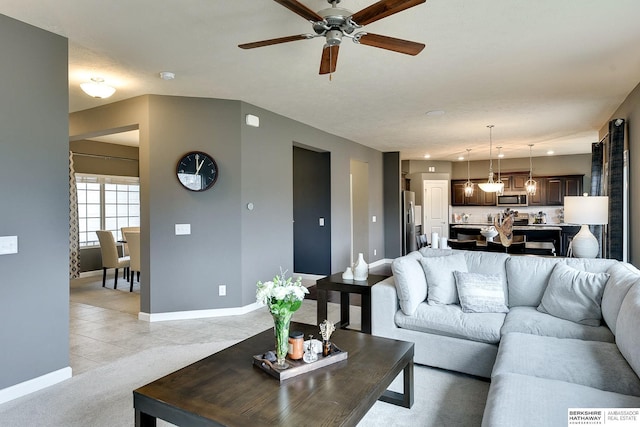 living room featuring light tile patterned floors, ceiling fan, light carpet, and baseboards