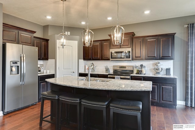 kitchen with dark brown cabinets, dark wood-style flooring, stainless steel appliances, and a sink