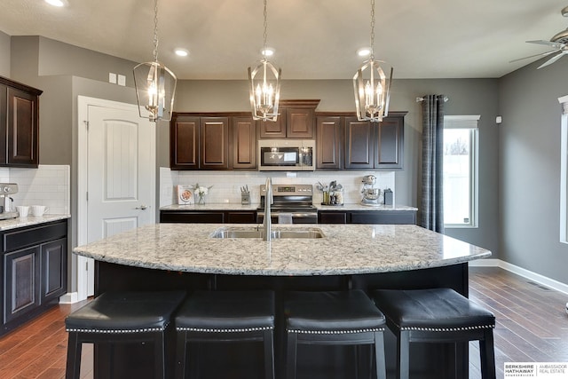 kitchen with stainless steel appliances, a breakfast bar area, and dark wood-style floors