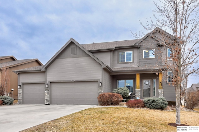 craftsman-style house featuring a garage, driveway, a shingled roof, and a front yard