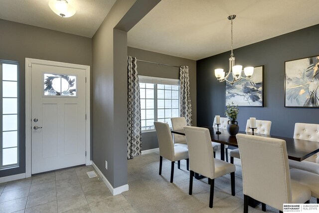 dining space with light tile patterned floors, baseboards, and an inviting chandelier