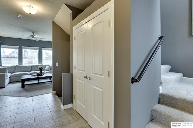 staircase with carpet, a ceiling fan, a textured ceiling, tile patterned flooring, and baseboards