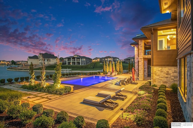 pool featuring a patio area, a water view, and a residential view