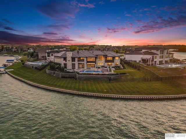 back of property at dusk featuring a water view and a residential view