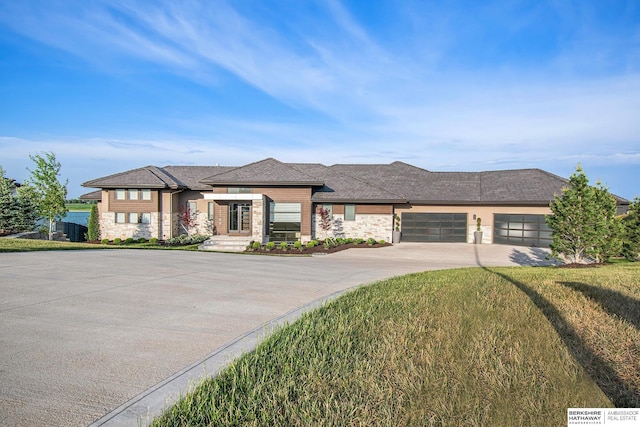 prairie-style house with a front yard, concrete driveway, and an attached garage