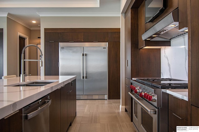 kitchen with premium appliances, extractor fan, a sink, and modern cabinets