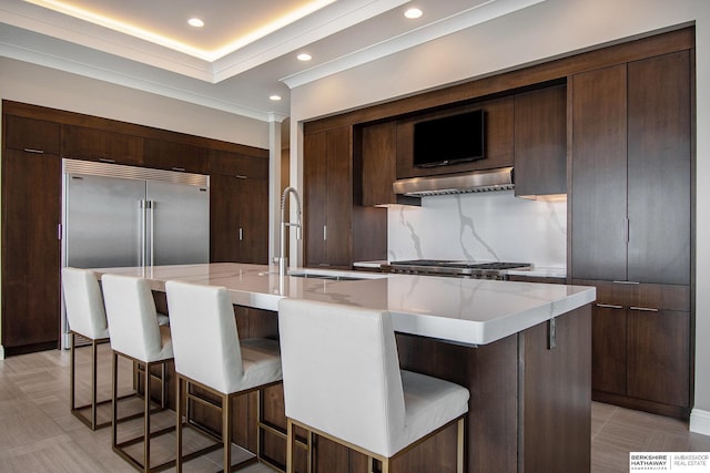 kitchen with a spacious island, modern cabinets, a breakfast bar, range hood, and a sink