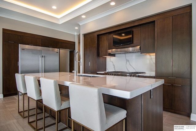 kitchen with a breakfast bar, a kitchen island with sink, a sink, and modern cabinets