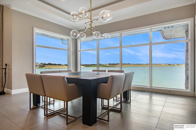 dining area with a tray ceiling, a water view, visible vents, a chandelier, and baseboards