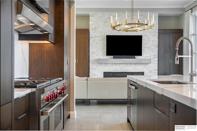 kitchen with stainless steel appliances, a sink, hanging light fixtures, ventilation hood, and modern cabinets