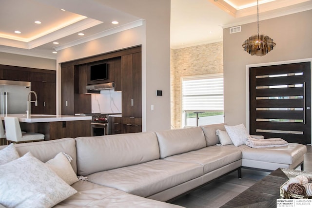 living area with recessed lighting, a raised ceiling, visible vents, and crown molding