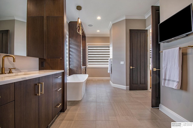 bathroom with crown molding, a freestanding tub, vanity, and baseboards