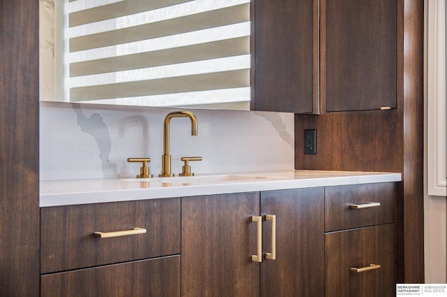 kitchen with dark brown cabinetry, modern cabinets, light countertops, and a sink