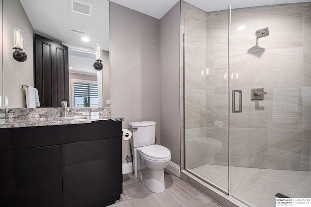 full bath with toilet, vanity, a shower stall, and visible vents