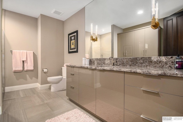 bathroom with visible vents, toilet, a shower stall, vanity, and baseboards