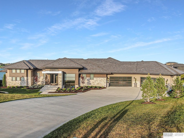 prairie-style home featuring a garage, a front lawn, and concrete driveway