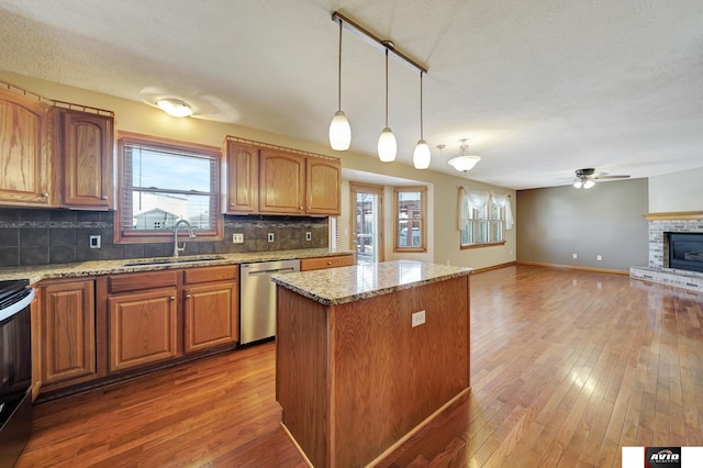 kitchen featuring stainless steel appliances, hanging light fixtures, open floor plan, a kitchen island, and a sink