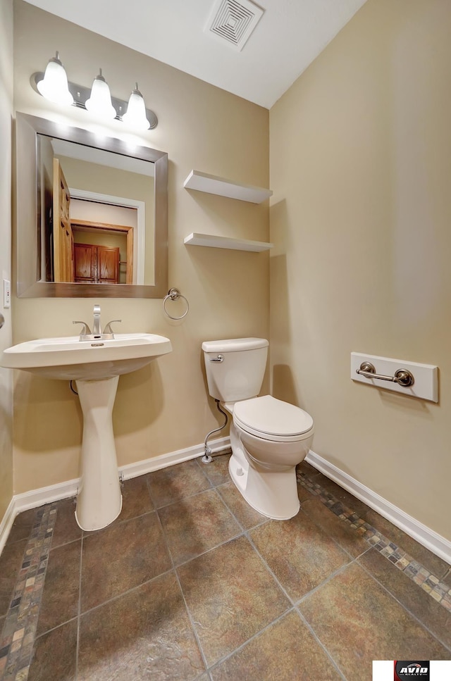 half bathroom featuring toilet, visible vents, and baseboards